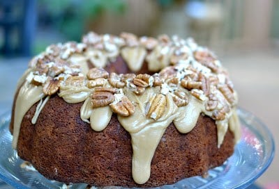 Apple Cream Cheese Bundt Cake with cream cheese glaze and sliced almonds on a blue plate, overhead view