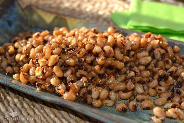 Crispy fried black eyed peas with charred edges piled on a blue plate with green napkin in background