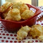 Golden coconut macaroons in red fish-shaped dish on red and white polka dot napkin with macaroons scattered on surface