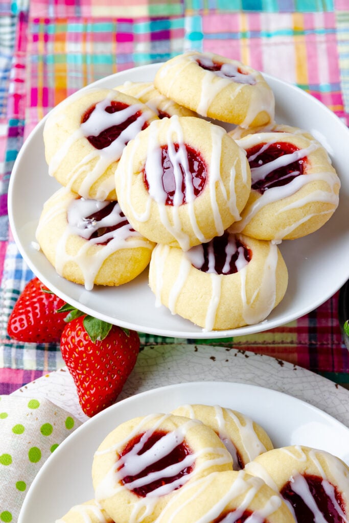 Jam Thumbprint Cookies on a white plate with stawberries.