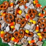 Candy Corn Snack Mix with pretzels, cereal, and candy corn on green leaf-shaped plate, overhead view