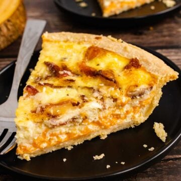 Sloce of Bacon Cheddar Quiche on a plate with a fork.