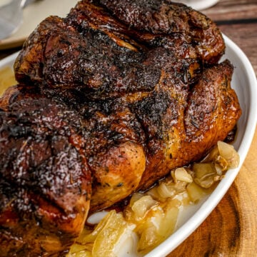 Slow Cooker Balsamic Brown Sugar Glazed Pork Roast on white plate with caramelized onions, served on wooden surface