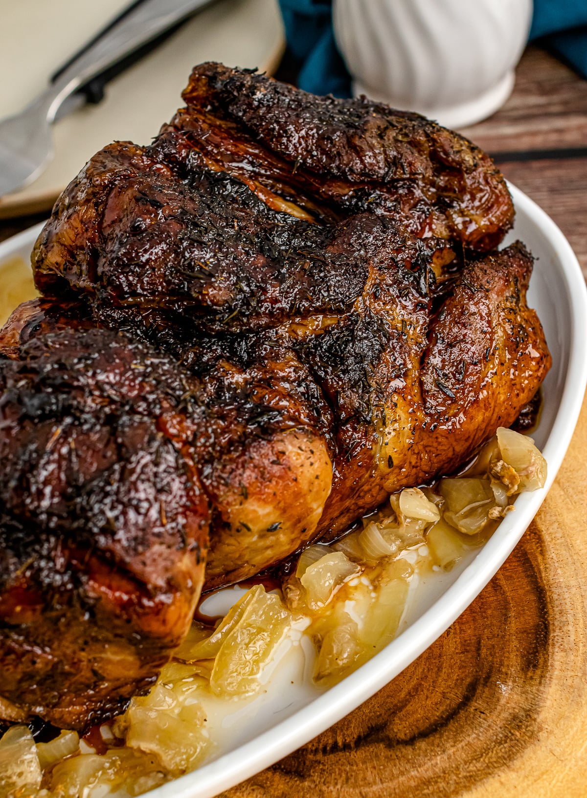 Slow Cooker Balsamic Brown Sugar Glazed Pork Roast on white plate with caramelized onions, served on wooden surface