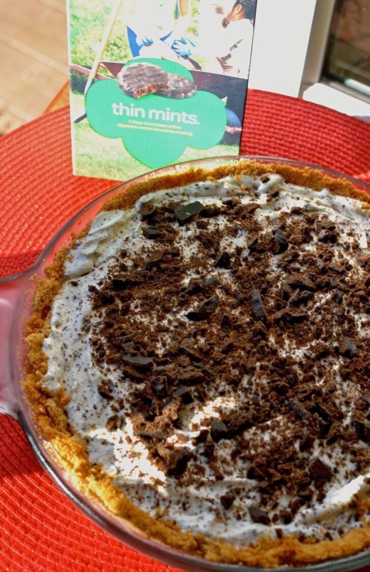 Thin Mints Ice Cream Pie with graham cracker crust, creamy filling, and crushed cookie topping in glass pie dish on red placemat