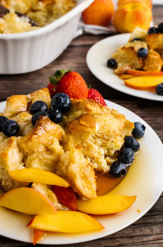 French Toast Bread Pudding on a plate with peaches and berries.