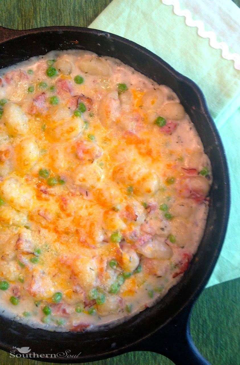 Gnocchi with Ham & Peas in creamy sauce served in a cast iron skillet, topped with melted cheese and peas