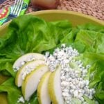 Pear & Blue Cheese Salad in yellow bowl with fresh lettuce, sliced pears, and crumbled blue cheese, fork and beverage visible