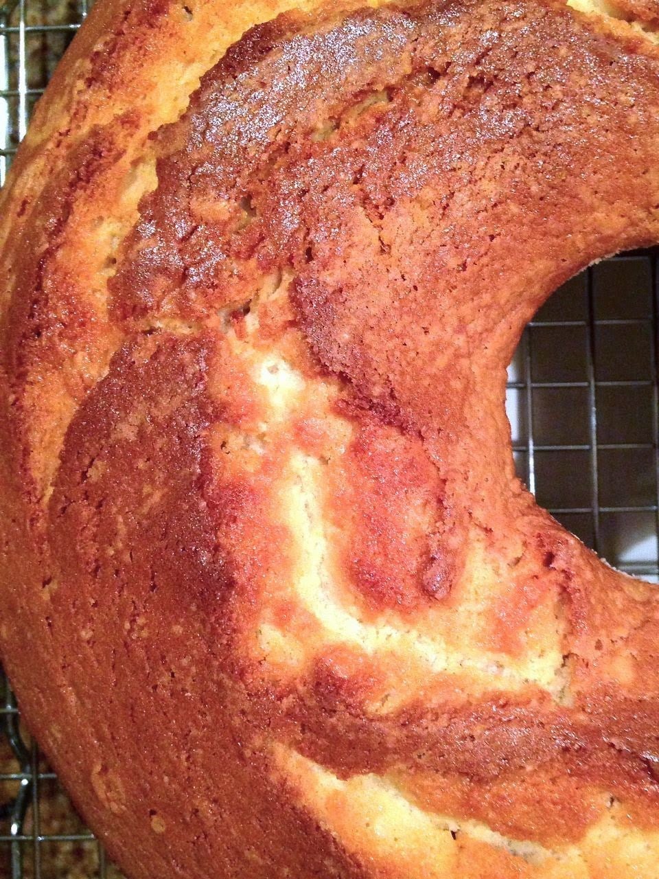 Brown Sugar & Cream Cheese Pound Cake cooling on wire rack, showing dense crumb with cinnamon swirl and powdered sugar dusting