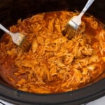 Shredded buffalo chicken in a slow cooker with two forks for serving, showing the 5-Ingredient Crock Pot Buffalo Chicken recipe result