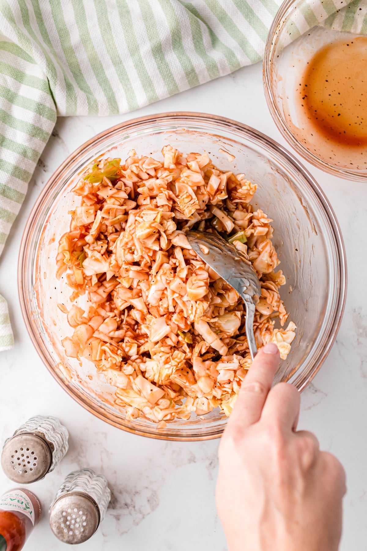 BBQ red slaw mixing with a spoon in a mixing bowl.