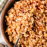 Carolina BBQ Red Slaw in wooden bowl with serving spoon and striped kitchen towel nearby
