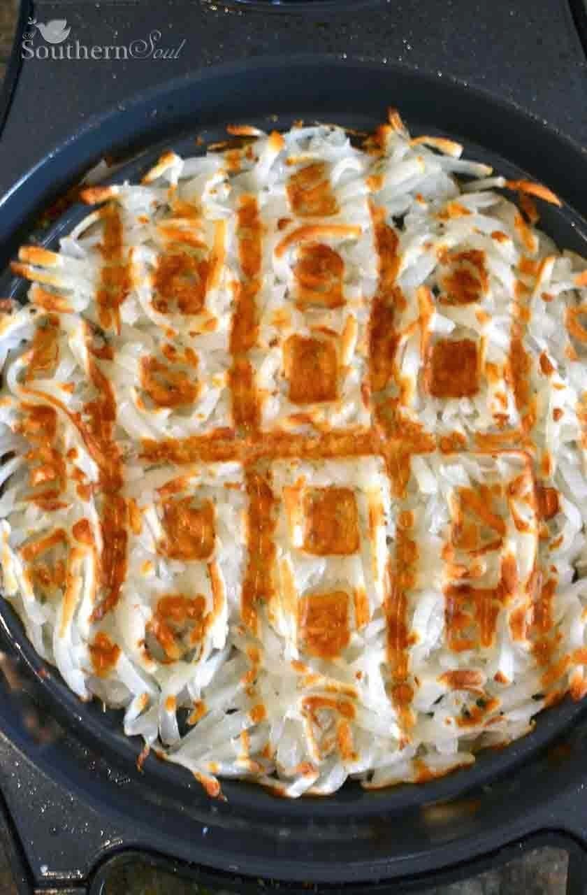 Waffle Iron Hash Browns cooked golden brown in cast iron skillet, overhead view with crispy edges and white interior visible