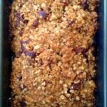 Oatmeal Brown Sugar Banana Bread baked in dark loaf pan, topped with oats and nuts, fresh from oven in Southern baking dish