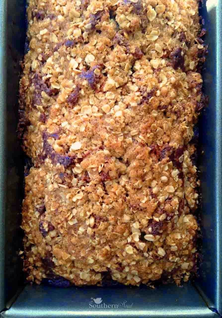 Oatmeal Brown Sugar Banana Bread baked in dark loaf pan, topped with oats and nuts, fresh from oven in Southern baking dish