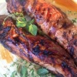 Grilled Pork Tenderloin With Fresh Herb Marinade sliced on a plate, garnished with fresh rosemary and thyme sprigs