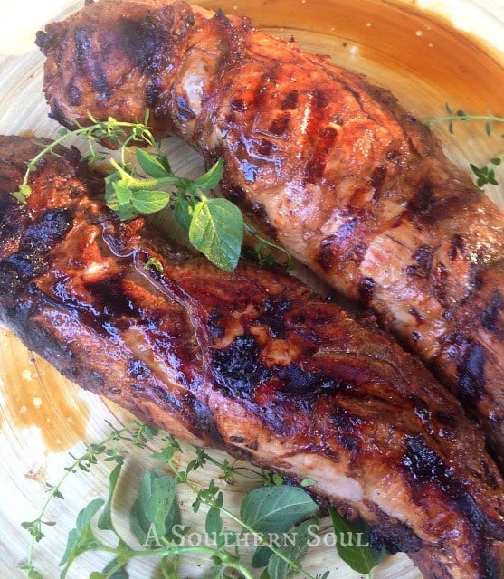 Grilled Pork Tenderloin With Fresh Herb Marinade sliced on a plate, garnished with fresh rosemary and thyme sprigs