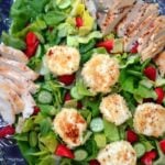 Grilled Chicken and Goat Cheese Salad with Strawberry Vinaigrette served on a decorative blue plate with sliced chicken, crispy goat cheese
