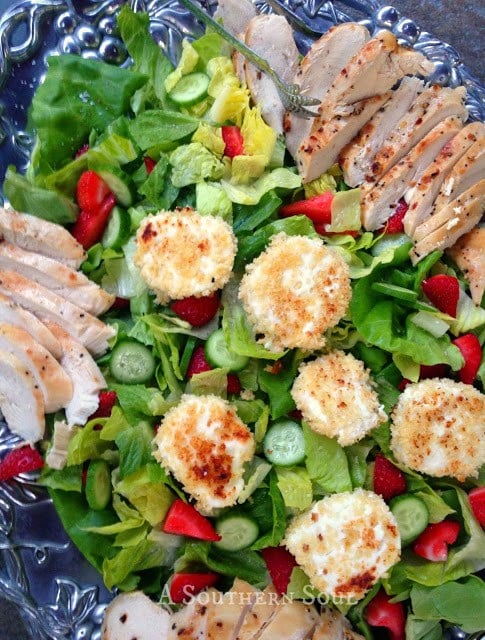 Grilled Chicken and Goat Cheese Salad with Strawberry Vinaigrette served on a decorative blue plate with sliced chicken, crispy goat cheese