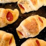 Pizza Crescent Bites baked on a dark griddle with red peppers, melted cheese, and black pepper seasoning