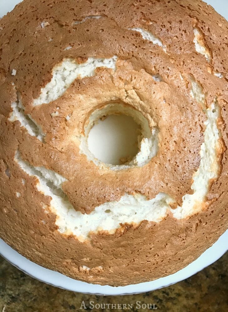 Overhead view of a chocolate angel food cake with white frosting swirls on a white plate from A Southern Soul blog