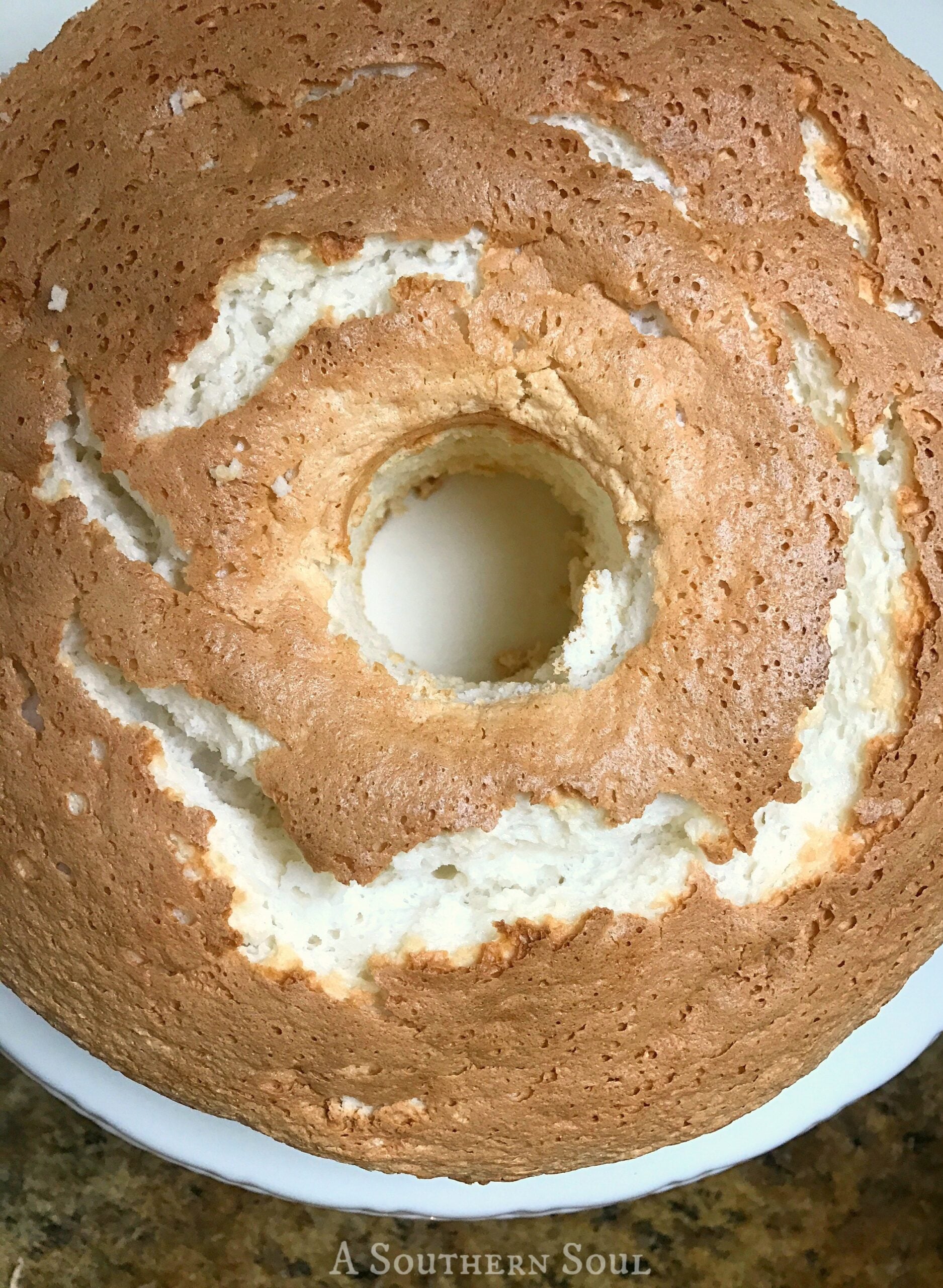 Overhead view of a chocolate angel food cake with white frosting swirls on a white plate from A Southern Soul blog