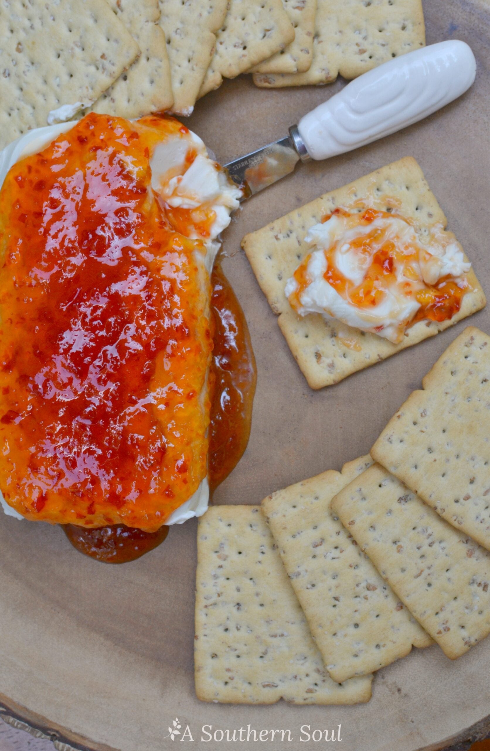 Pepper Jelly & Cream Cheese Appetizer with seeded crackers, featuring a generous dollop of cream cheese topped with vibrant red pepper jelly