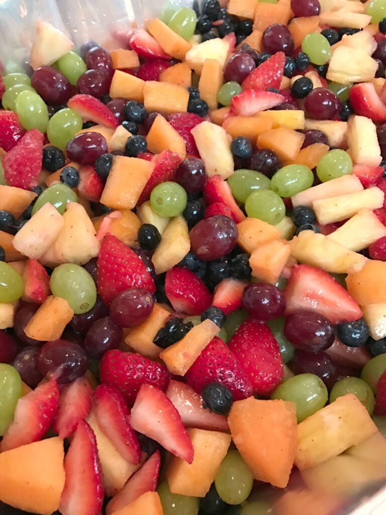 Colorful fruit salad with strawberries, grapes, blueberries, cantaloupe, and pineapple chunks mixed together in a bowl