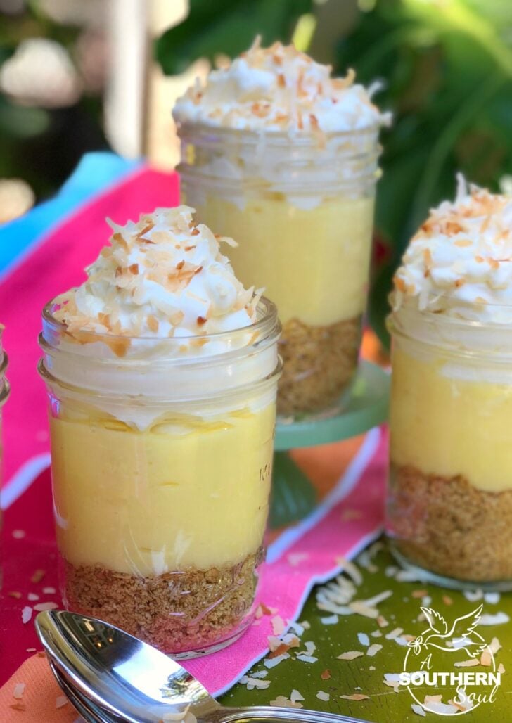 No Bake Coconut Cream Pie In Jars with graham cracker crust, creamy custard filling, whipped cream, and toasted coconut flakes in glass jars