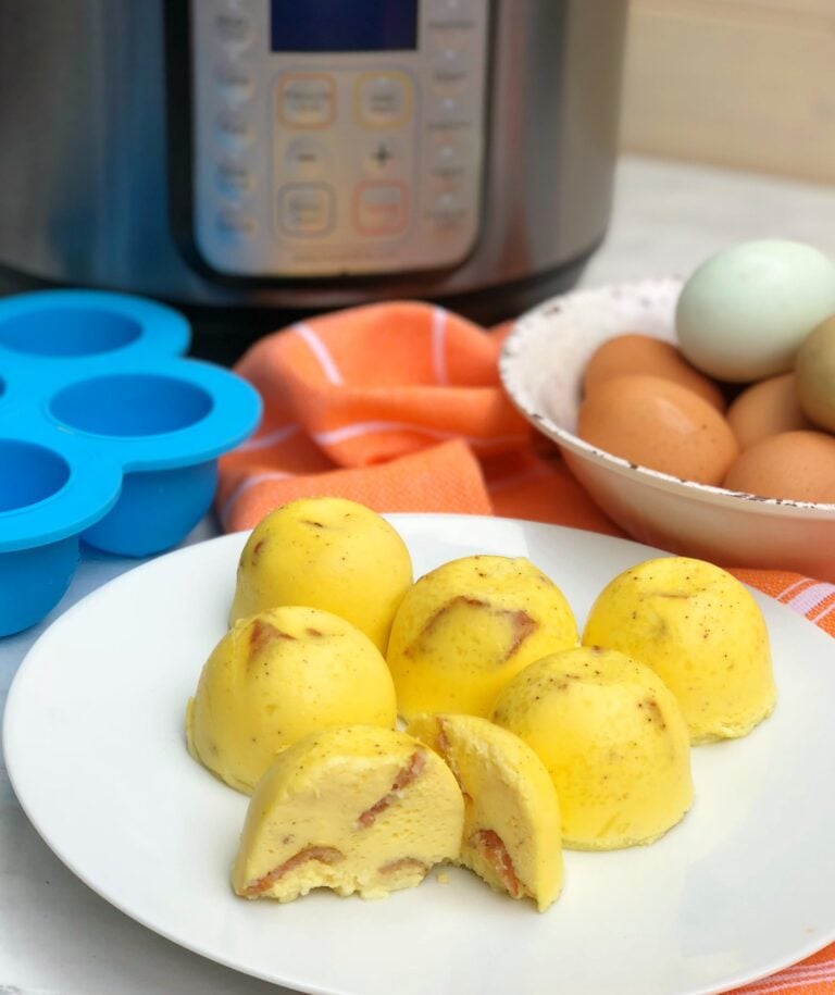 Instant Pot Bacon & Cheese Egg Bites on white plate with eggs, silicone molds, and pressure cooker in background