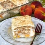 Slice of Peaches & Cream Icebox Cake on glass plate with fork, showing layers of wafers, whipped cream, and peaches; fresh peaches and full