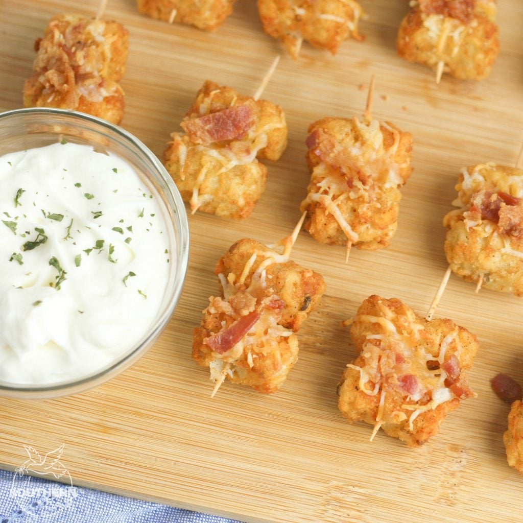 Tater Tots made into loaded little appetizer bites are a great appetizer or snack. Topped with cheese & bacon then dipped into creamy sour cream, they become a savory treat everyone will love.