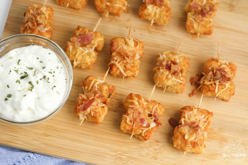 Tater Tots made into loaded little appetizer bites are a great appetizer or snack. Topped with cheese & bacon then dipped into creamy sour cream, they become a savory treat everyone will love.