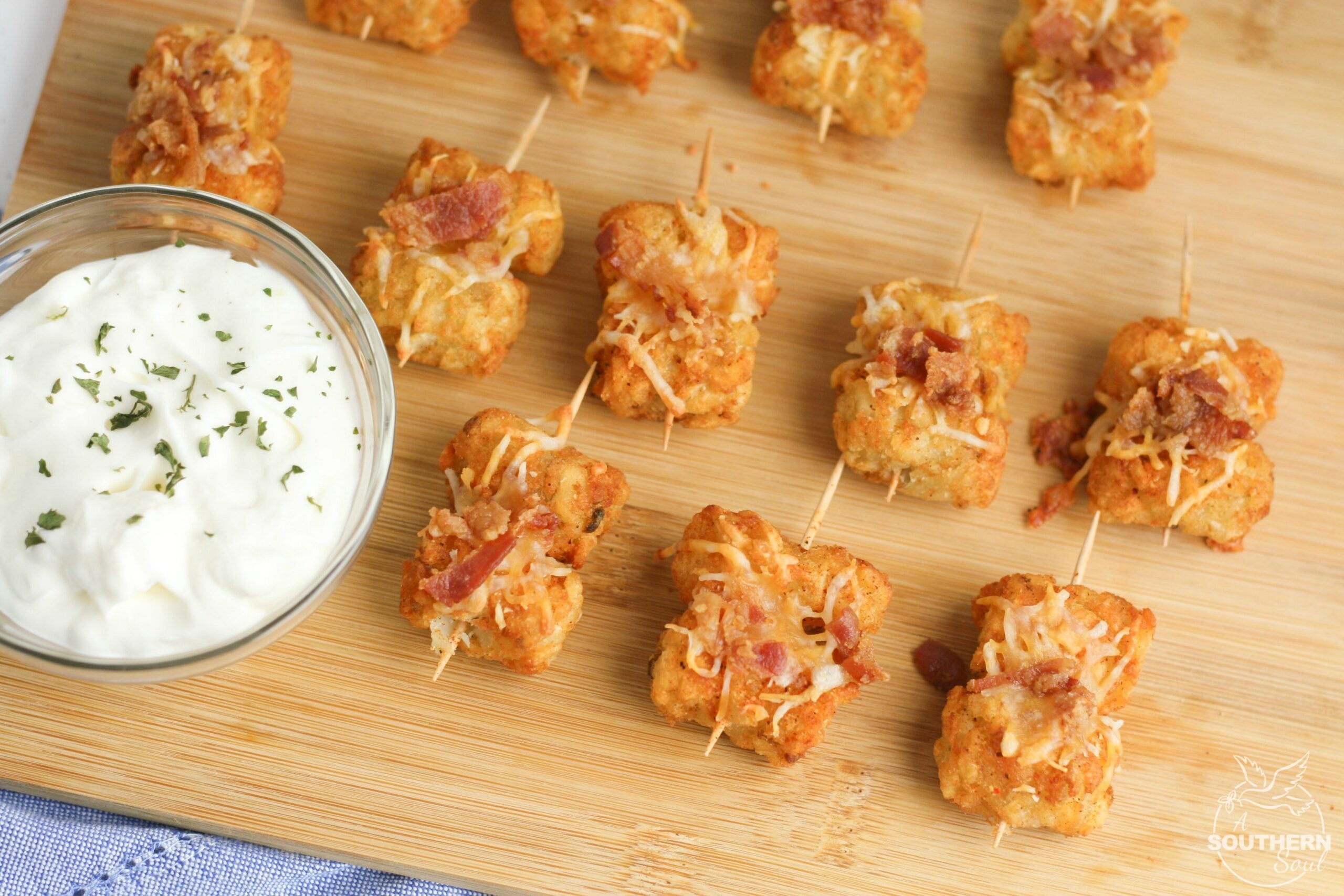 Tater Tots made into loaded little appetizer bites are a great appetizer or snack. Topped with cheese & bacon then dipped into creamy sour cream, they become a savory treat everyone will love.