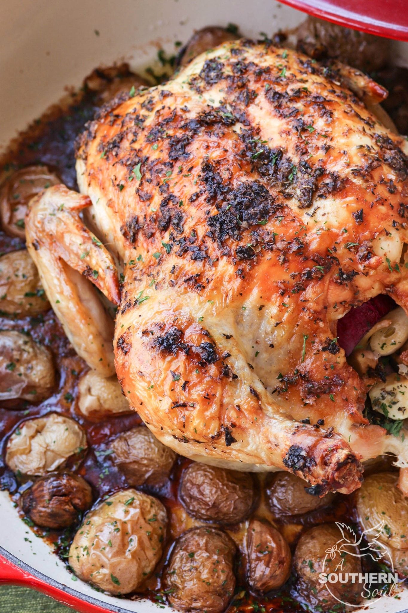 Herb butter with thyme, basil and oregano flavors a whole chicken roasted in the oven on a bed of new potatoes.