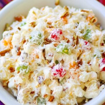 Ambrosia salad made with oranges, cherries, pineapple and marshmallows is tossed in a light fluffy mixture of fresh whipped cream with a touch of sour cream for extra flavor.