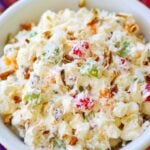 Ambrosia salad made with oranges, cherries, pineapple and marshmallows is tossed in a light fluffy mixture of fresh whipped cream with a touch of sour cream for extra flavor.