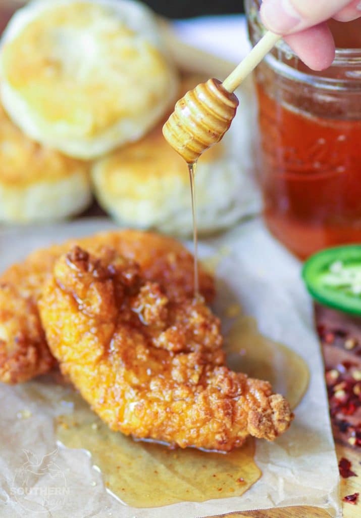 Simple to make and crazy delicious, Hot Honey is drizzled over two pieces of perfectly fried chicken with biscuits served as a side.