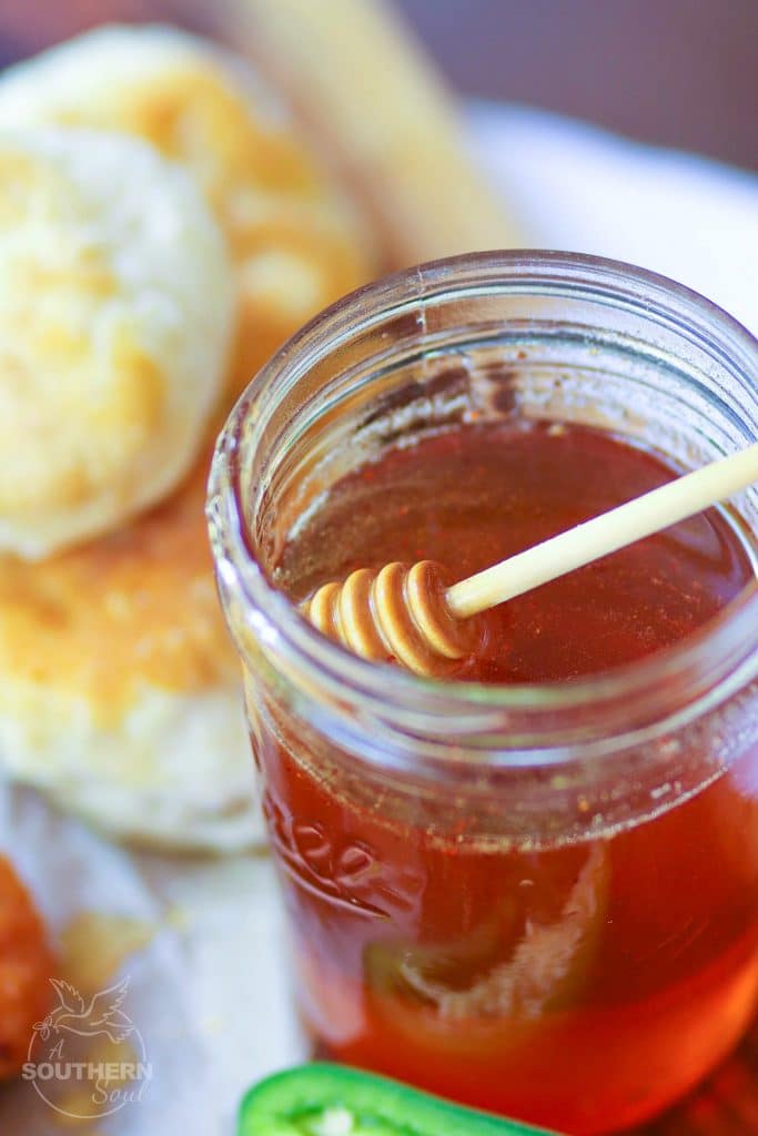 Rich, spicy, sweet Hot Honey is placed into a mason jar, waiting to be drizzled over fried chicken or biscuits.