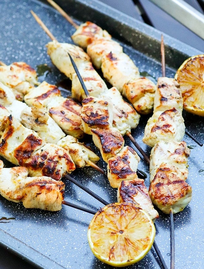 Grilled Chicken Souvlaki Skewers are juicy and tender. Make with lemon juice, oregano, garlic, salt and pepper. Add in a chopped salad with tomatoes, onions and cucumbers and you've got a meal your friends and family will love!