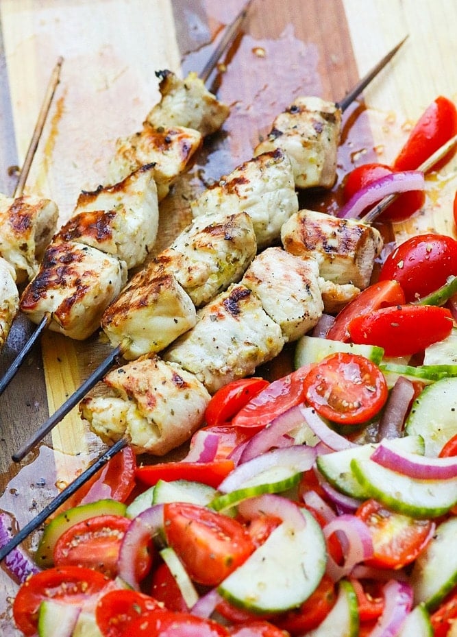 Grilled Chicken Souvlaki Skewers are juicy and tender. Make with lemon juice, oregano, garlic, salt and pepper. Add in a chopped salad with tomatoes, onions and cucumbers and you've got a meal your friends and family will love!