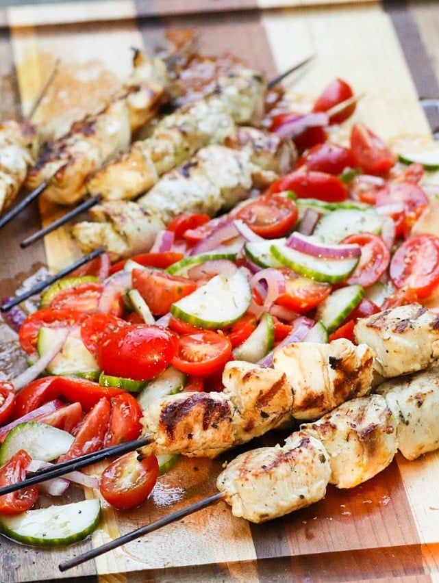 Grilled Chicken Souvlaki Skewers are juicy and tender. Make with lemon juice, oregano, garlic, salt and pepper. Add in a chopped salad with tomatoes, onions and cucumbers and you've got a meal your friends and family will love!