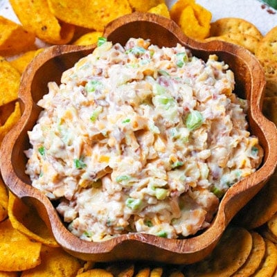 Million Dollar Dip in wooden flower-shaped bowl surrounded by crispy tortilla chips, topped with green onions