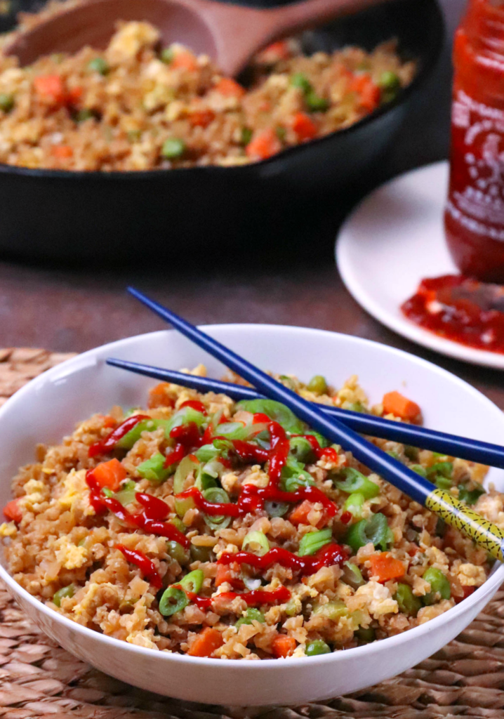 Cauliflower Fried Rice is a low carb version of your favorite Chinese take out dish. Made with cauliflower, eggs, carrots, and peas, it's seasoned with soy sauce and garlic all ready in less than 20 minutes!