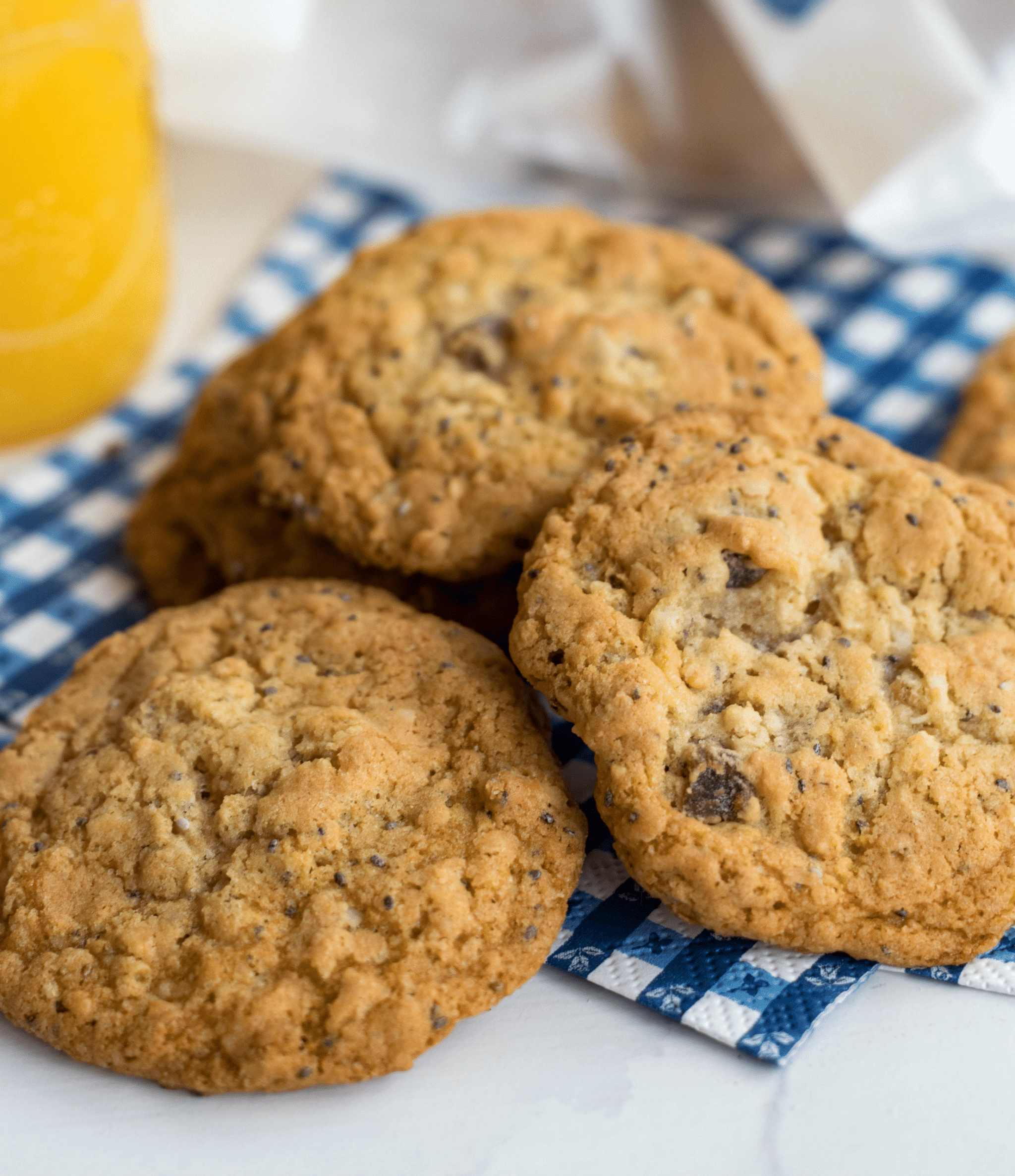 Oatmeal Breakfast Cookies with chocolate chips on blue checkered napkin beside orange juice and napkins