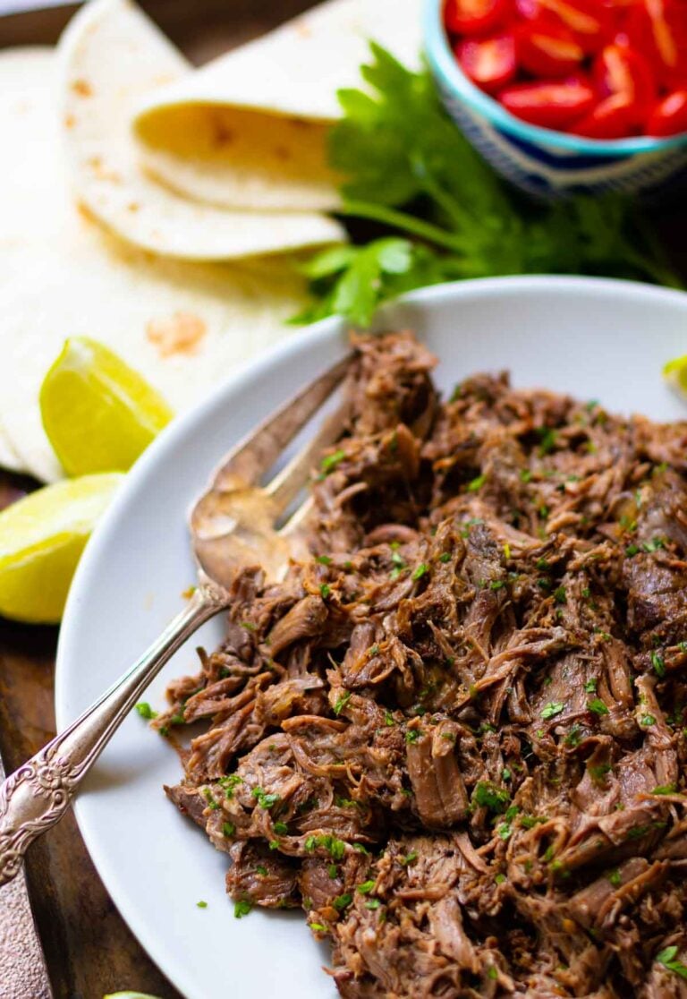 Slow Cooker Mexican Shredded Beef is easy to make and perfect for tacos, nachos, burritos or served with rice and beans. Make with chuck roast, chipolte peppers, onions, lime juice, beef stock, taco seasoning and garlic.