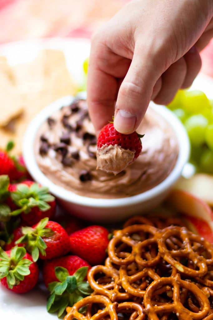Hand holding strawberry dipped in Chocolate Dip.