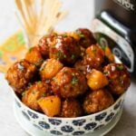 Crock Pot Hawaiian Meatballs in a bowl with the slow cooker and skewers.