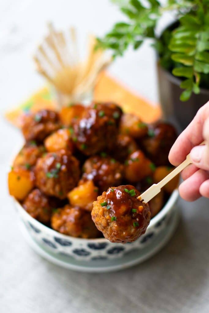 Crock Pot Hawaiian Meatballs with sauce on a small skewer.