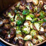 Perfectly cooked brussel sprouts in the basket of an air fryer.